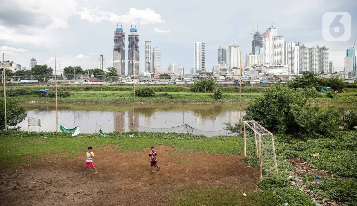 Sejumlah anak bermain di lapangan bola yang terdapat di Bantaran Banjir Kanal Barat Kawasan Petamburan, Jakarta, Minggu (12/12/2021). Taman di bantaran kali kawasan padat penduduk itu menjadi sarana bermain bagi anak-anak di sekitarnya. (Liputan6.com/Faizal Fanani)