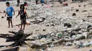 <p>Anak-anak berjalan melewati plastik dan sampah lainnya yang terdampar di Pantai Kedonganan, Kabupaten Badung, Bali, Indonesia, Rabu (12/4/2023). (SONNY TUMBELAKA/AFP)</p>