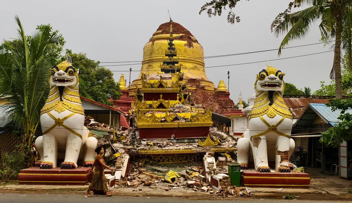 Seorang wanita berjalan melewati pagoda Buddha yang rusak di Inn Wa di pinggiran Mandalay pada 6 April 2025. (Foto oleh AFP)