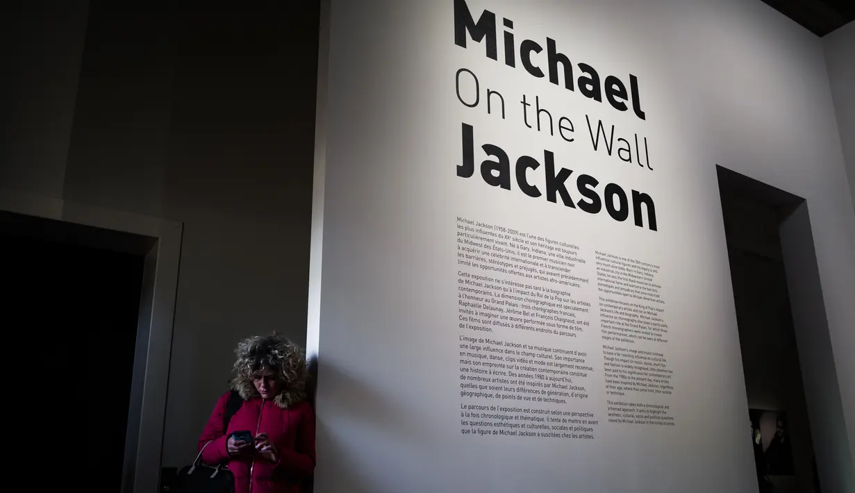 Seorang wanita bersandar di dinding pintu masuk pameran Michael Jackson: On The Wall di museum Grand Palais, Paris, Rabu (21/11). Pameran menampilkan karya seni yang terinspirasi oleh lagu, koreografi dan video klip Michael Jackson. (Philippe LOPEZ/AFP)