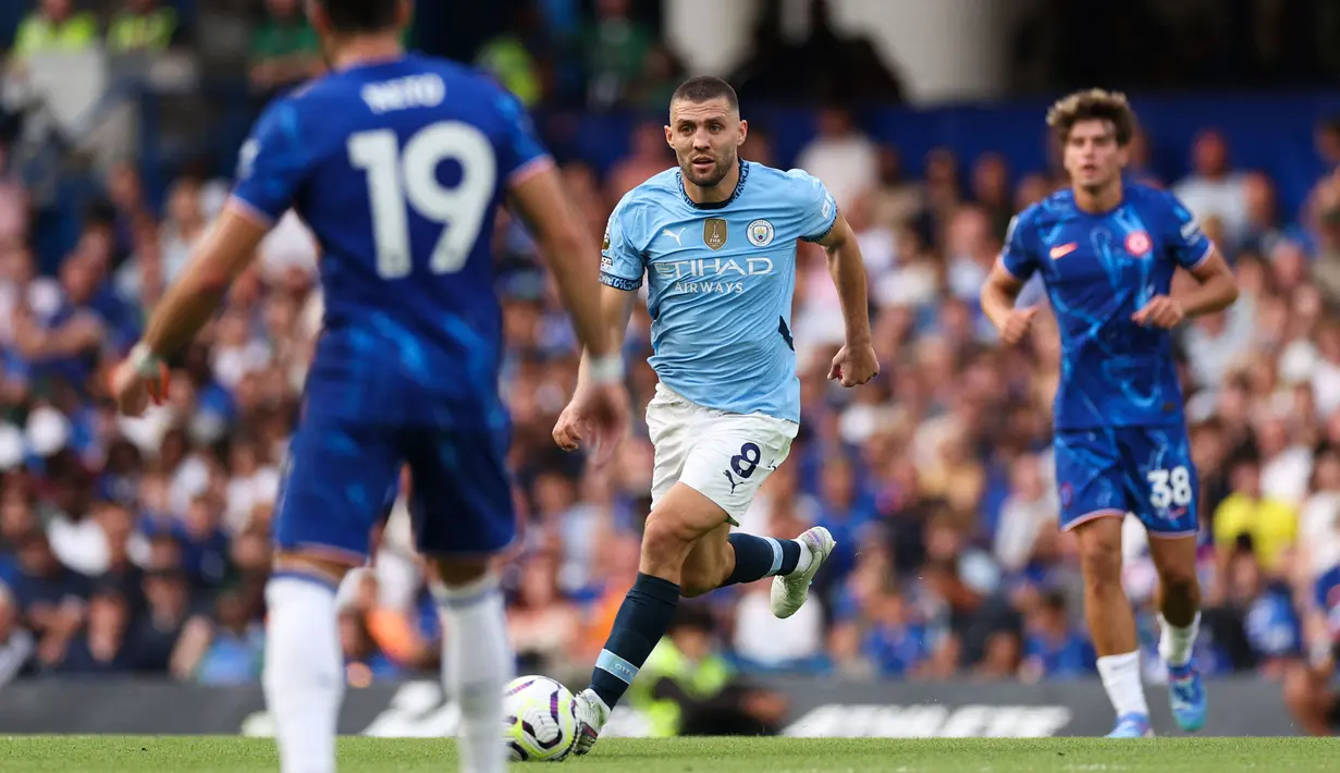 Pemain Manchester City, Mateo Kovacic menggiring bola melewati sejumlah pemain Chelsea pada laga Liga Inggris 2024/2025 di Stamford Bridge, London, Inggris, Minggu (18/08/2024) malam WIB. (AFP/Adrian Dennis)