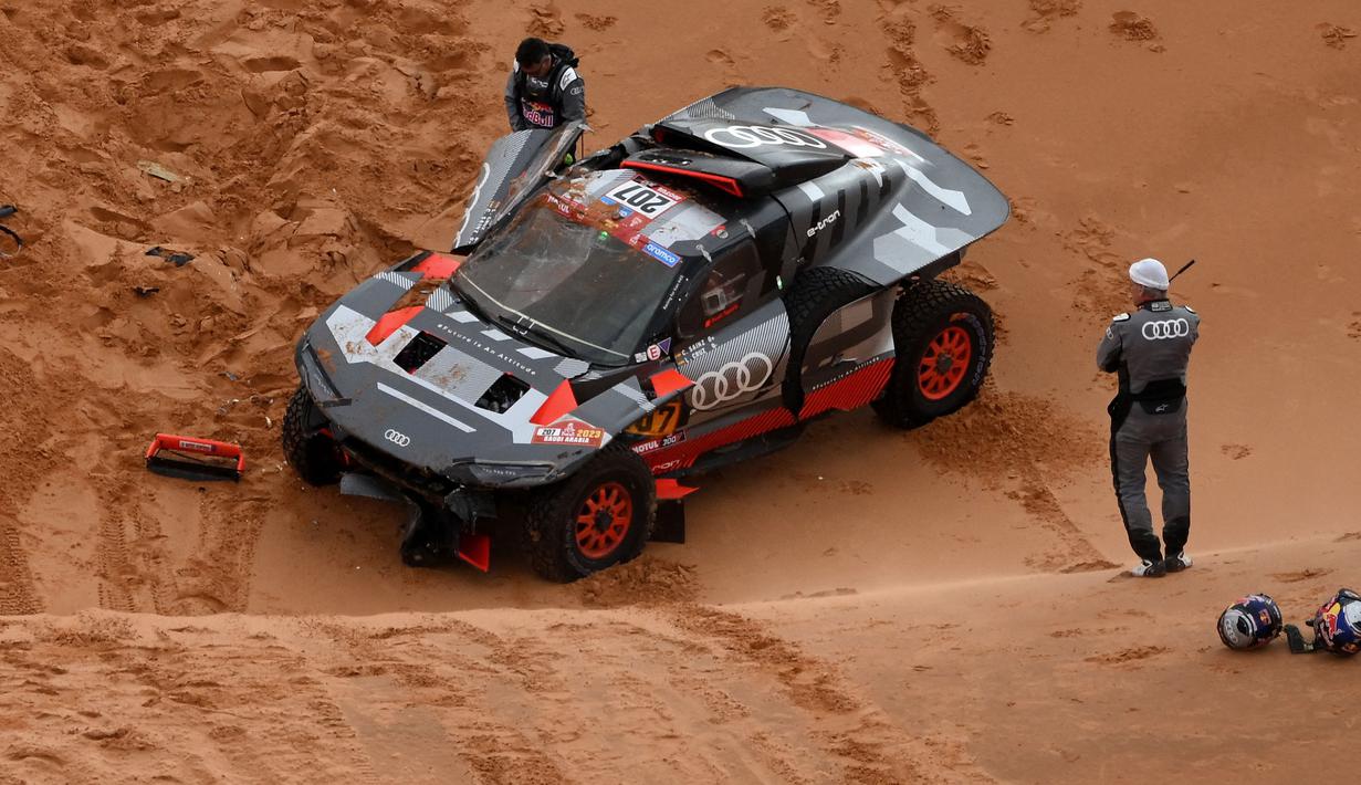 Carlos Sainz dan co-driver Luca Cruz bisa keluar dari mobil dengan selamat. Mereka juga sempat membalikkan mobil dibantu dengan beberapa penonton di sana. (AFP/Franck Fife)