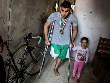 Atlet sepeda asal Palestina, Alaa Al-Daly berjalan menggunakan kruk di rumahnya di Rafah, Jalur Gaza, 19 April 2018. Impian atlet 21 tahun itu untuk berkompetisi di ajang Asian Games seketika pupus karena kaki kanannya diamputasi. (AFP/SAID KHATIB)