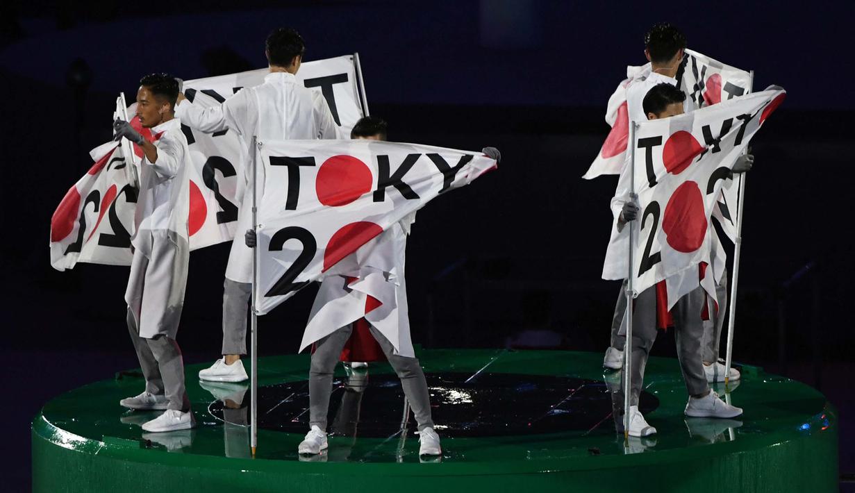 Penari membentangkan bendera berlogo Olimpiade Tokyo 2020 saat acara penutupan Olimpiade Rio 2016 di Stadion  Maracana, Rio de Janeiro, (22/8/2016). (AFP/Greg Baker)