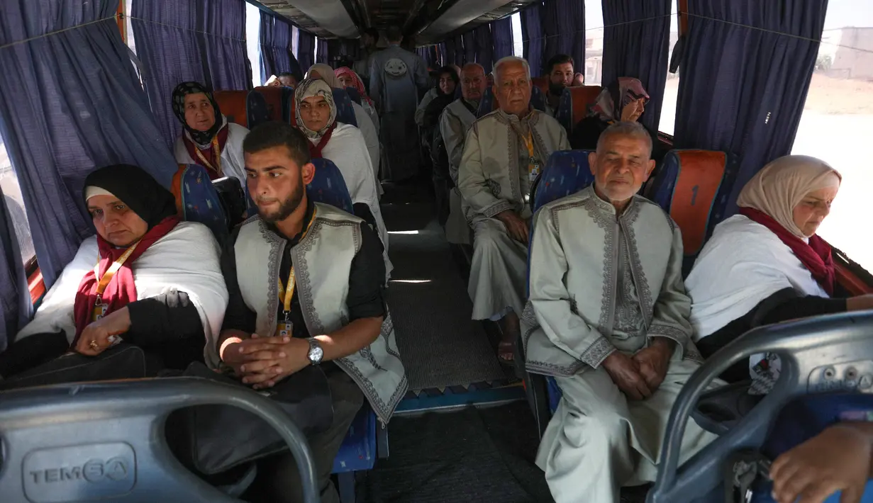 Warga Suriah dari provinsi Idlib, berada di dalam  bus untuk menuju Tanah Suci Makkah di kota Binnish, Senin (22/7/2019). Jemaah calon haji asal Suriah melakukan perjalanan ke Arab Saudi untuk menjalankan ibadah haji dari perbatasan Bab al-Hawa yang berseberangan dengan Turki. (Omar HAJ KADOUR/AFP)