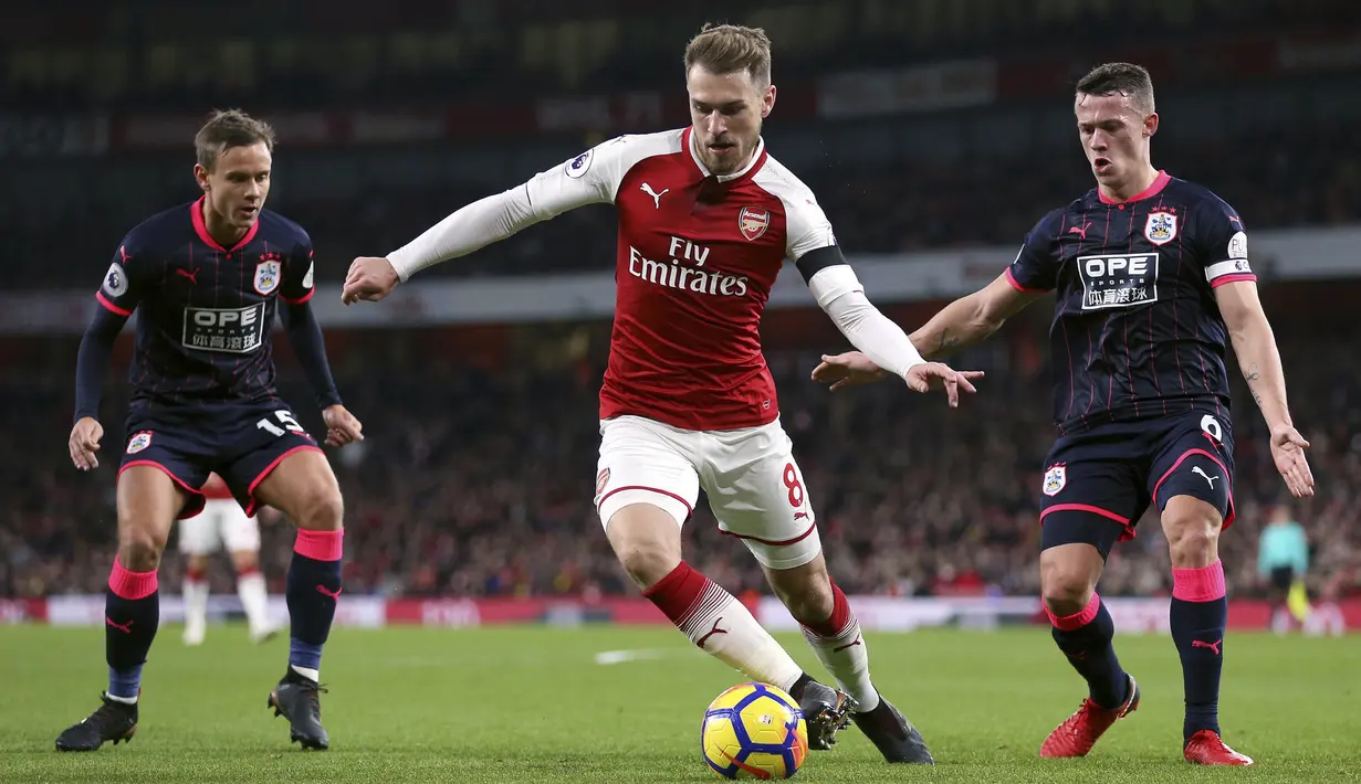 Gelandang Arsenal, Aaron Ramsey, berusaha melewati penjagaan pemain Huddersfield pada laga Premier League di Stadion Emirates, London, Rabu (29/11/2017). Arsenal menang 5-0 atas Huddersfield. (AP/Nigel French)