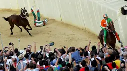 Seorang joki terjatuh saat beraksi dalam lomba pacuan kuda tahunan Palio di Siena, Italia. (Reuters/Fabio Muzzi)