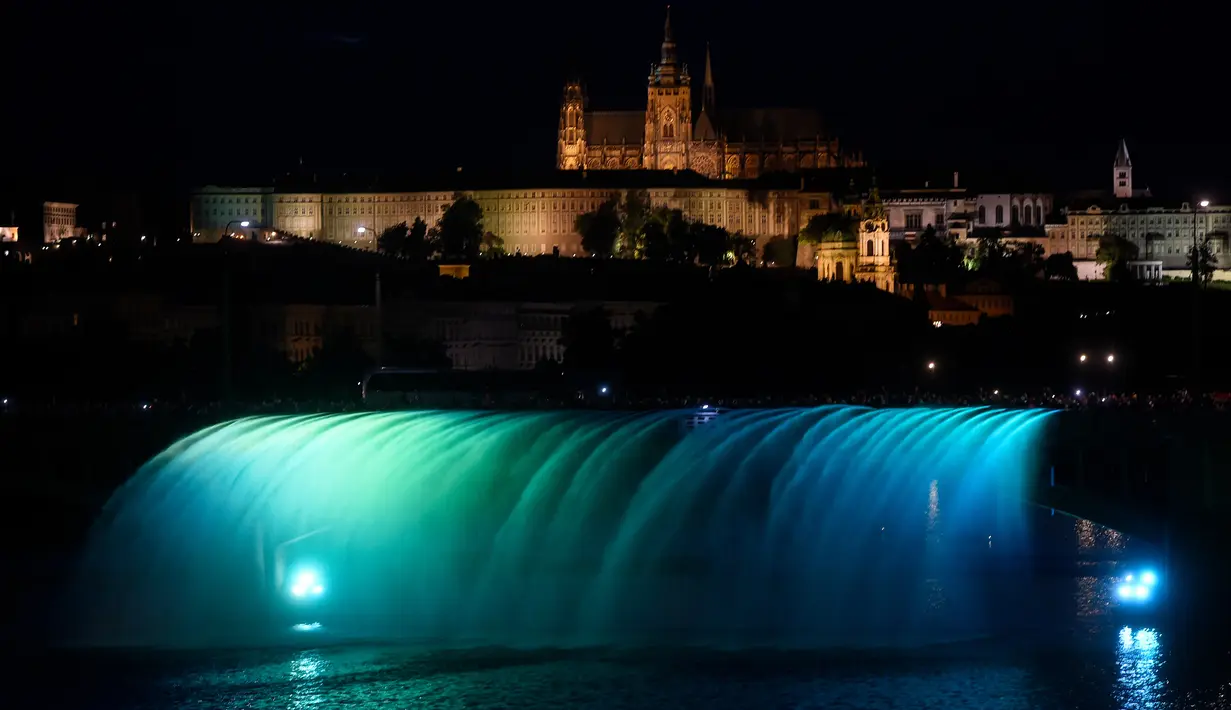 Petugas pemadam kebakaran menyemprotkan air ke Sungai Vltava berhias cahaya hijau untuk menandai HUT ke-100 Ceko di Praha, Sabtu (2/6). (Michal Cizek/AFP)