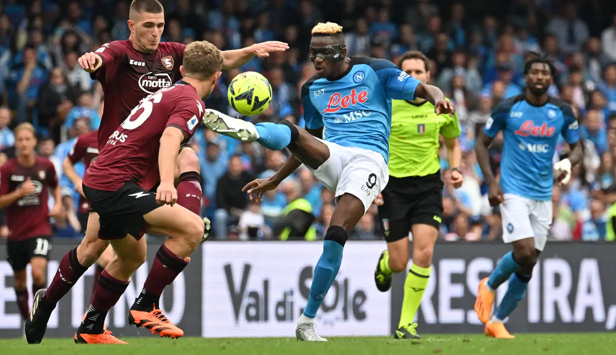 Striker Napoli, Victor Osimhen mengontrol bola di depan dua pemain Salernitana pada laga Liga Italia 2022/2023 di Diego Armando Maradona Stadium, Naples (30/4/2023). Victor Osimhen hingga kini telah mencetak 21 gol dan 5 assist dari seluruh 26. Ia mulai terancam posisinya oleh Lautaro Martinez karena gagal menambah gol dalam 5 laga terakhir bersama Napoli. (AFP/Filippo Monteforte)