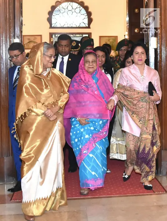 Ibu Negara Iriana Joko Widodo berjalan sambil bergandengan tangan bersama Ibu Negara Bangladesh, Rasyidah Khanam di Credential Hall, Bangabhan Presidential Palace (27/1). (Liputan6.com/Pool/Rusman Biro Pers Setpres)