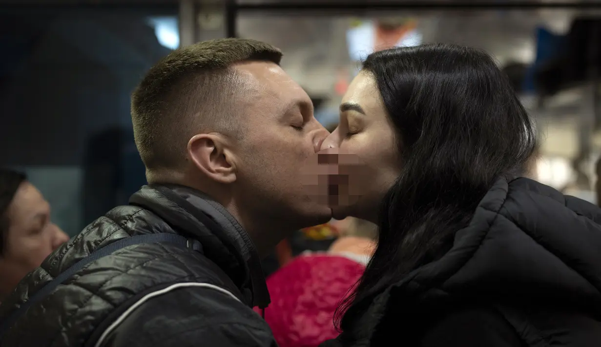 Nicolai (41) mencium istrinya Lolita saat mengucapkan selamat tinggal di kereta menuju Polandia untuk melarikan diri dari perang di stasiun kereta di Lviv, Ukraina, 15 April 2022. Banyak warga Ukraina mencari perlindungan ke Polandia dan negara-negara tetangga lainnya. (AP Photo/Emilio Morenatti)