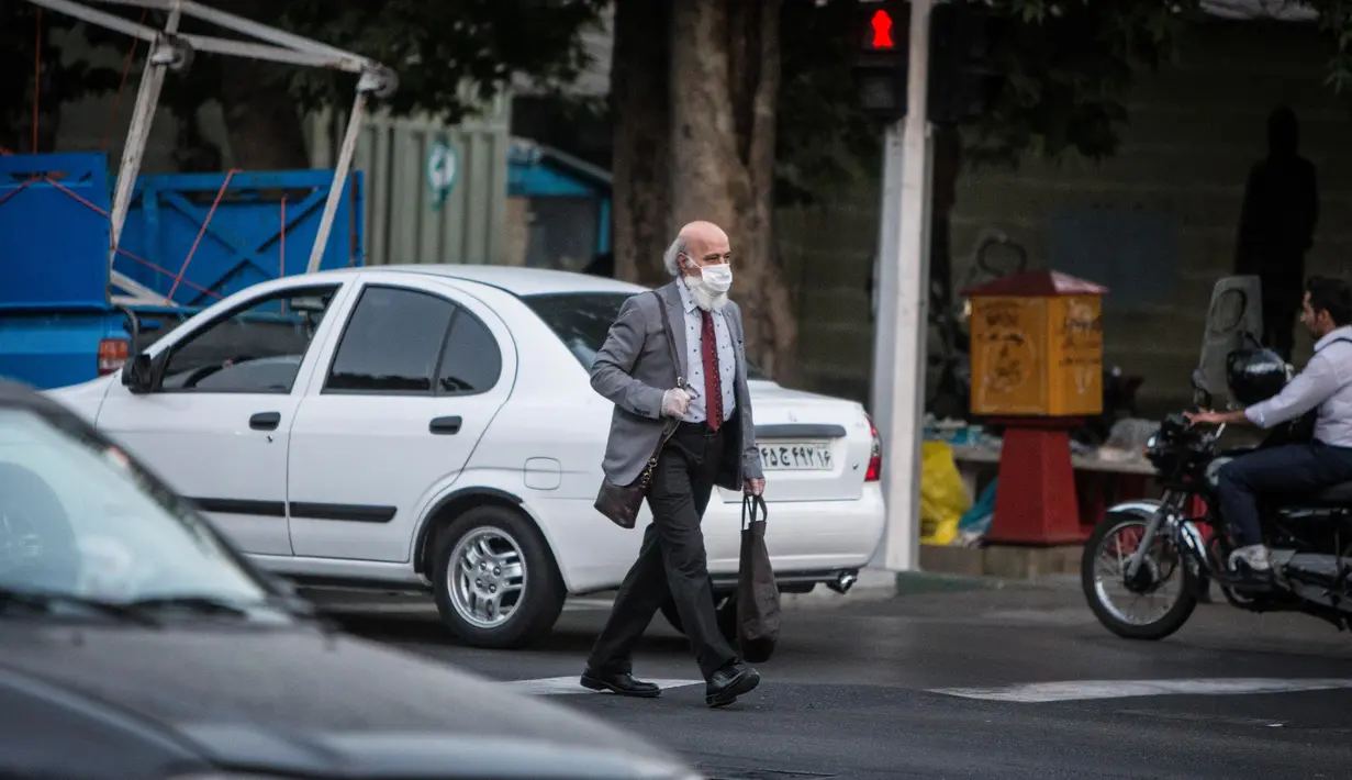 Seorang pria dengan masker menyeberangi jalan di pusat Kota Teheran, 28 Juni 2020. Presiden Iran Hassan Rouhani pada Minggu (28/6) mengatakan mengenakan masker di tempat umum akan menjadi wajib mulai pekan depan di tengah meningkatnya kasus dan kematian akibat COVID-19. (Xinhua/Ahmad Halabisaz)