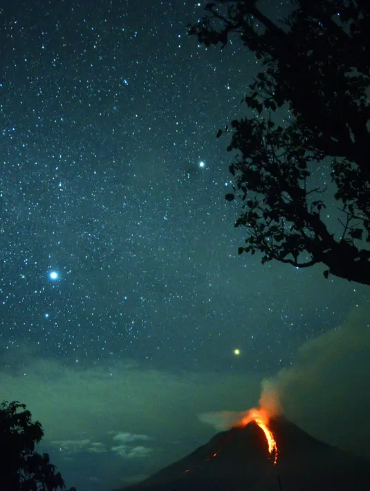 Foto yang diambil dengan exposure yang lama menunjukkan, cahaya bintang menerangi langit berpadu dengan Gunung Sinabung yang sedang memuntahkan lahar di Karo, Sumatera Utara (28/12). (AFP/Lana Priatna)