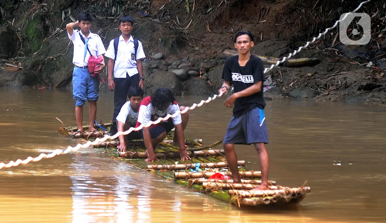 Sejumlah siswa menyeberangi Sungai Cikaniki dengan rakit di Rumpin, Bogor, Jawa Barat, Rabu (15/1/2020). Akibat banjir bandang merobohkan jembatan yang menghubungkan Desa Tonjong Rumpin dan Desa Kantalarang Leuwiliang, warga terpaksa memanfaatkan perahu rakit untuk melintas (merdeka.com/Arie Basuki)