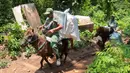Para petugas pemilu menggunakan kuda untuk membawa kotak suara dan perlengkapan pemilu lainnya ke tempat pemungutan suara di desa-desa terpencil di Andongrejo, Jawa Timur, Selasa, 13 Februari 2024. (AP Photo/Trisnadi)