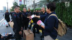 Relawan TKN Jokowi-Ma'ruf Amin membagikan multivitamin kepada aparat kepolisian yang melakukan penjagaan di Bundaran HI, Jakarta, Jumat (24/5/2019). Mereka juga membagikan makanan berbuka puasa sebagai bentuk kepedulian untuk aparat yang telah menjaga keamanan di Jakarta. (Liputan6.com/Angga Yuniar)