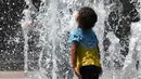Seorang anak bermain di bawah guyuran air mancur saat gelombang panas menyapu seluruh Eropa utara di Montpellier, Prancis, Selasa (31/7). Sebagian wilayah Prancis telah menjadi daerah waspada tinggi karena meningkatnya gelombang panas. (AFP/PASCAL GUYOT)