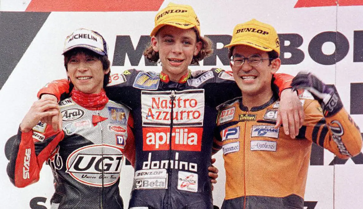 Pebalap MotoGP asal Italia, Valentino Rossi (tengah) merayakan gelar juara 125 cc di Sirkuit Shah Alam, Malaysia, Minggu (13/3/1997). (AFP/Francis Silvan)