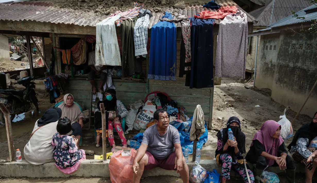 Sebelumnya, banjir bandang melanda Kabupaten Aceh Tamiang pada Rabu 26 November 2025. Tampak dalam foto, Warga menunggu untuk menerima bantuan di Aceh Tamiang, Minggu 14 Desember 2025. (Yasuyoshi CHIBA/AFP)