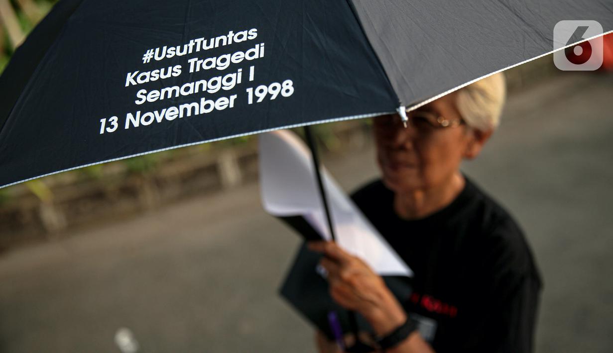 Anggota Jaringan Solidaritas Korban untuk Keadilan (JSKK) menggunakan payung hitam bertuliskan #UsutTuntas "Kasus Tragedi Semanggi I 13 November 1998 saat melakukan Aksi Kamisan ke-795 di seberang Istana Merdeka, Jakarta, Kamis (16/11/2023). (Liputan6.com/Faizal Fanani)