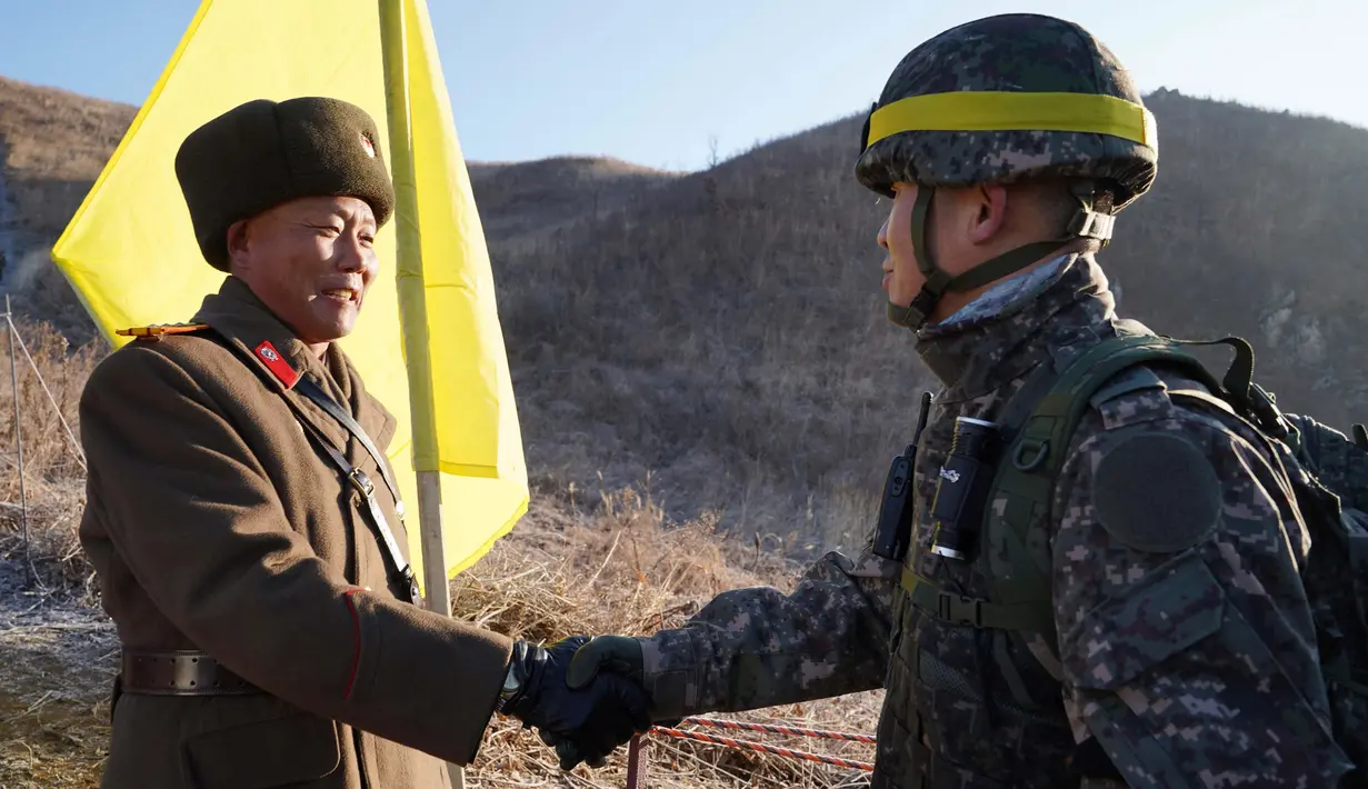 Tentara Korea Selatan berjabat tangan dengan tentara Korea Utara  sebelum melintasi Garis Demarkasi Militer di Cheorwon, Rabu (12/12). Mereka mulai memeriksa pembongkaran pos-pos penjaga di Zona Demiliterisasi. (HANDOUT/AFP/SOUTH KOREAN DEFENCE MINISTRY)