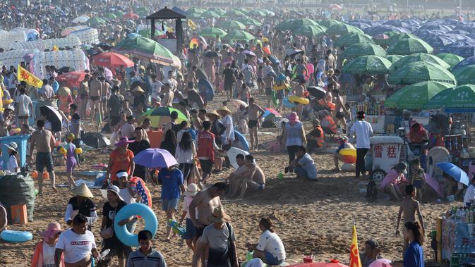 Orang-orang memadati pantai untuk mendinginkan diri di Qingdao, China timur, pada 3 Agustus 2019. Banyak warga di Negeri Tirai Bambu memanfaatkan musim panas dengan mengunjungi pantai untuk mengisi liburan. (Photo by FRED DUFOUR / AFP)