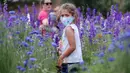 Seorang gadis Mia Liddell (7) mengenakan masker di tengah kekhawatiran penyebaran COVID-19 saat menikmati sepetak bunga liar Texas di Richardson, Texas, Selasa, (28/4/2020). (AP Photo / LM Otero)