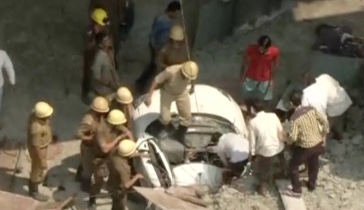 Petugas mengevakuasi mobil yang terjebak reruntuhan jembatan layang yang ambruk di Kolkata, India, Kamis (31/3). Petugas dan warga saat ini tengah mencoba menyelamatkan mereka yang tertimpa reruntuhan logam dan beton. (REUTERS/ANI via Reuters)