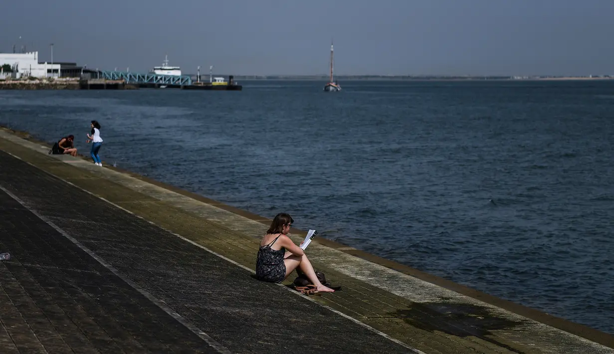 Seorang wanita membaca buku di Ribeira das Naus, Lisbon (3/8). Suhu tertinggi tercatat di Eropa adalah 48 derajat di Athena tahun 1977, diikuti 47,3 di Amareleja, Portugal 2003 serta di Montoro, Spanyol tahun lalu. (AFP Photo/Patricia De Melo Moreira)