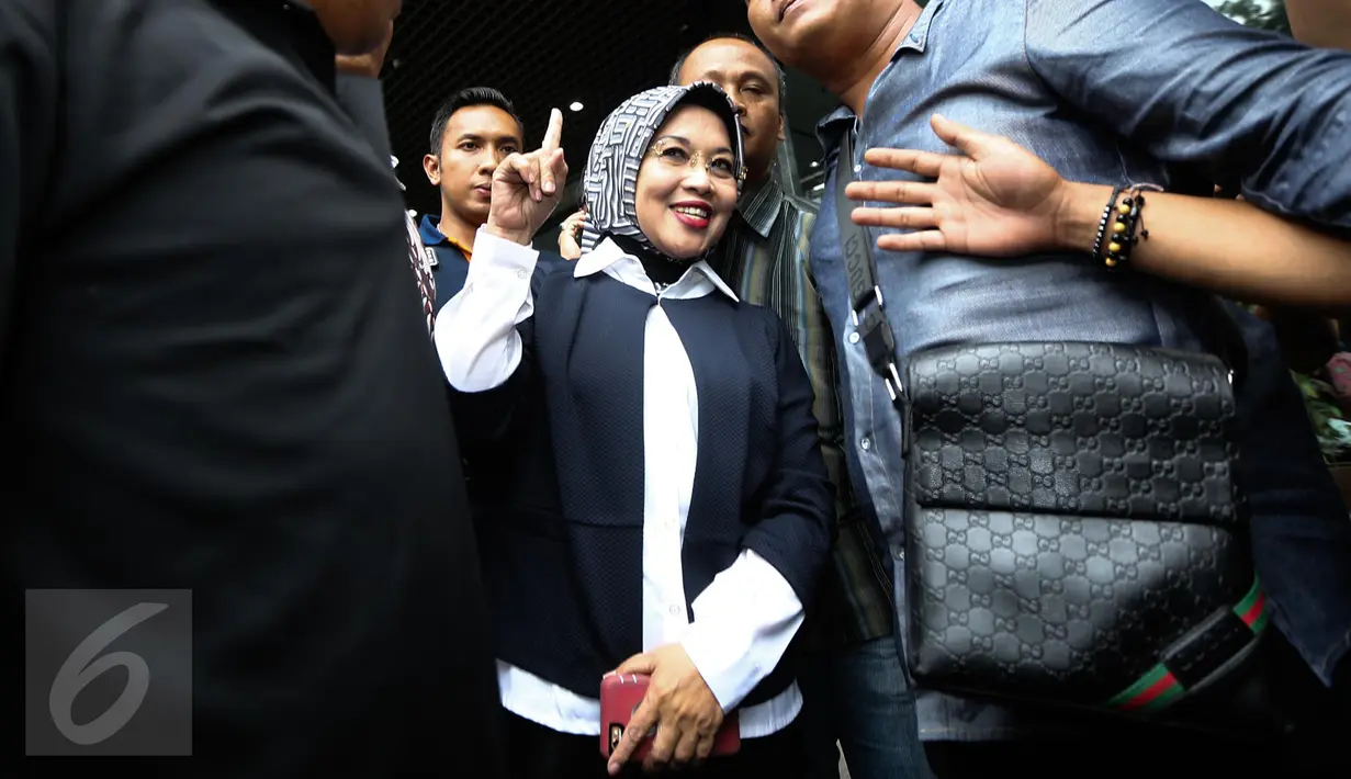 Sylviana Murni berpose sambil mengacungkan jarinya saat akan meninggalkan Gedung Ombudsman, Jakarta, Senin (30/1). Panggilan tersebut terkait pemeriksaan kasus dugaan korupsi pembangunan Masjid Al-Fauz. (Liputan6.com/Faizal Fanani)