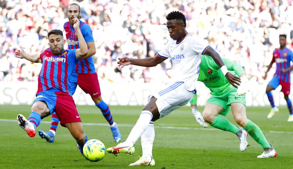 Pemain Barcelona Jordi Alba (kiri) mencoba untuk memblokir tendangan Real Madrid Vinicius Junior pada pertandingan La Liga Spanyol di Stadion Camp Nou, Barcelona, Spanyol, Minggu (24/10/2021). Real Madrid menang 2-1. (AP Photo/Joan Monfort)