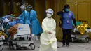 Seorang perawat (tengah) berjalan melewati pusat perawatan pasien sementara yang didirikan di luar Caritas Medical Centre, Hong Kong, Rabu (16/2/2022). Hong Kong menghadapi gelombang virus corona COVID-19 terburuk hingga saat ini. (Peter PARKS/AFP)