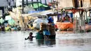 Warga membawa sepedanya melintasi banjir rob di jalan Yos Sudarso Semarang di kawasan Pelabuhan Tanjung Emas (24/4). Banjir akibat pasang air laut masih terjadi di sejumlah titik kota Semarang.  (Liputan6.com/Gholib)