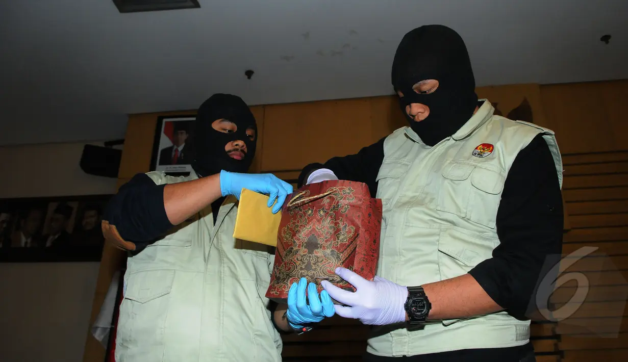 Dua orang penyidik KPK membawa kantong berisi uang suap yang diduga untuk anggota DPR Fraksi PDIP Adriansyah, Jakarta, Jumat (10/4/2015). KPK berhasil menangkap tangan pelaku saat bertransaksi di Bali.(Liputan6.com/Herman Zakharia) 