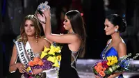 Miss Universe 2014, Paulina Vega saat mengambil kembali mahkota yang sempat disematkan ke Miss Kolombia, untuk diberikan kepada Miss Universe 2015, Pia Alonzo Wurtzbach di The AXIS Las Vegas, AS, Minggu (20/12). (Ethan Miller/Getty Images/AFP)