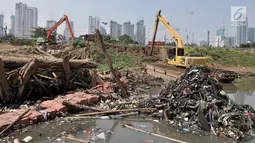 Alat berat terparkir dekat tumpukkan sampah yang muncul di permukaan Kanal Banjir Barat, Jakarta, Selasa (16/7/2019). Kemarau sejak dua bulan terakhir ini menyebabkan sampah-sampah yang mengendap di dasar sungai muncul ke permukaan sehingga menimbulkan bau tak sedap. (merdeka.com/Iqbal S Nugroho)