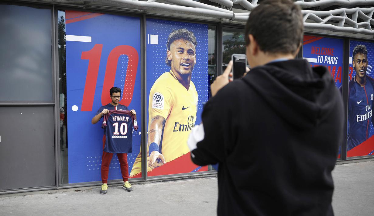 Seorang fans berfoto dengan memegang jersey Neymar Jr di depan toko merchandise di Paris, Jumat (4/8/2017). Setelah resmi bergabung dengan Paris Saint Germain, jersey Neymar Jr langsung diburu suporter klub Ibu kota. (AP/Kamil Zihnioglu)