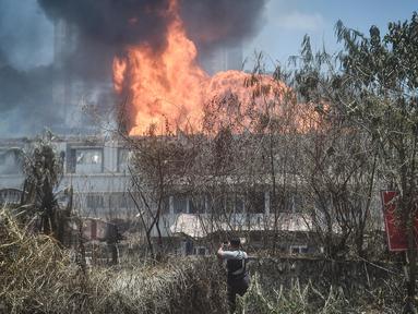 Seorang pria menyaksikan kebakaran yang disebabkan oleh kebocoran pipa gas di Puchong, Selangor, Malaysia pada 1 April 2025. (Arif Kartono/AFP)