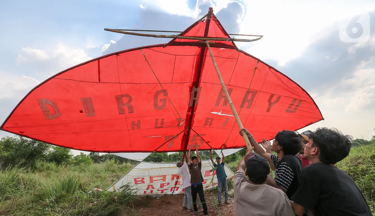 Warga menahan layang-layang merah putih raksasa sebelum diterbangkan di kawasan Bambu Apus, Tangerang Selatan, Senin (17/8/2020). Layangan dengan bahan bambu, kertas dan plastik tersebut diterbangkan dalam rangka memperingati HUT Ke-75 RI. (Liputan6.com/Fery Pradolo)