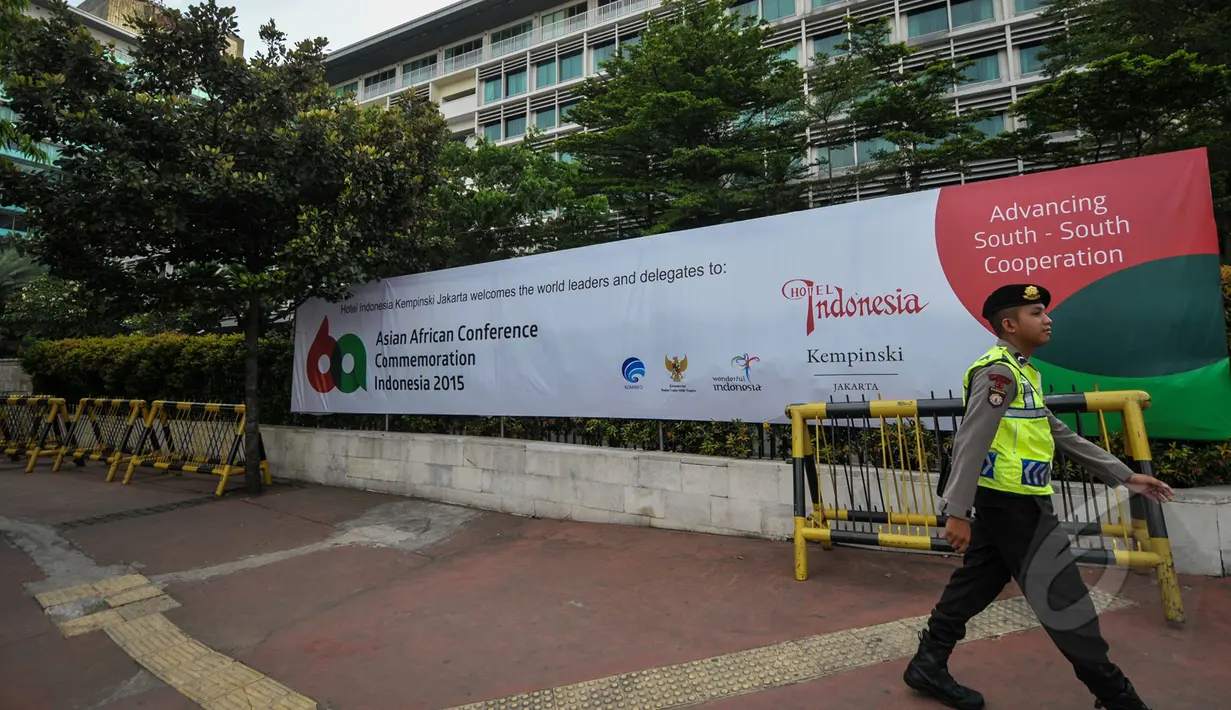 Seorang anggota kepolisian melintas di depan spanduk KAA di kawasan Senayan, Jakarta, Senin (20/4/2015). Pengamanan dilakukan untuk menjaga kelancaran KAA yang berlangsung 19-24 April 2015 di Jakarta dan Bandung. (Liputan6.com/Faizal Fanani)