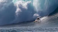 Peselancar Kohl Christensen menjelajah ombak besar di Pantai Utara O’ahu, Hawaii, Senin (26/11). (Brian Bielmann / AFP)