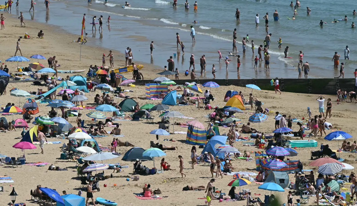 Para pengunjung berjemur menikmati sinar matahari di Pantai Bournemouth, Selatan Inggris pada Selasa 26 Mei 2026, saat kondisi gelombang panas menyebar ke sebagian wilayah tenggara Inggris dan London. (JUSTIN TALLIS/AFP)
