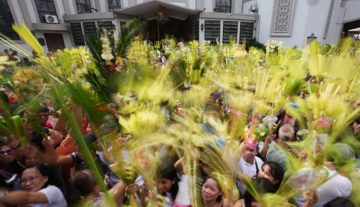 Para umat Kristiani mengacungkan daun palem mereka selama upacara pemberkatan di luar Katedral Antipolo, kota Antipolo, provinsi Rizal, Filipina, saat memperingati Minggu Palma, 29 Maret 2026. (AP Photo/Aaron Favila)