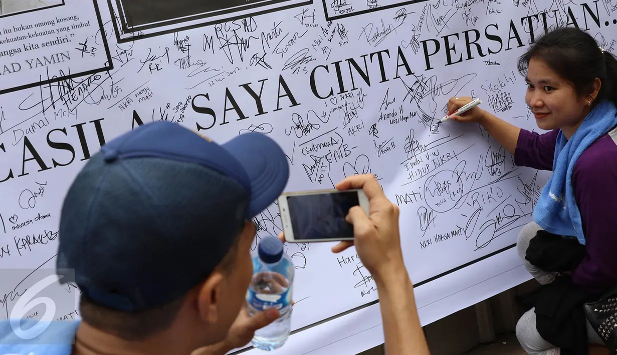 Warga berfoto dengan latar belakang spanduk bergambar tokoh nasional yang penuh tanda tangan di area car free day, Jakarta, Minggu (14/5). (Liputan6.com/Immanuel Antonius)