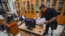 Berjalan dengan menggunakan tongkat besi, matanya terus menatap monitor-monitor komputer anak didik. Sesekali ia menghampiri komputer anak didik yang nampak kesulitan mengolah foto. Dengan penuh kesabaran, ia memberikan instruksi tahap demi tahap kepada beberapa muridnya yang menggunakan kursi roda yang juga mengalami celebral palsy (penurunan fungsi otak. (merdeka.com/Arie Basuki)