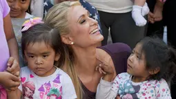 Paris Hilton tersenyum saat memeluk dua anak selama selama kunjungan bertemu tujuh keluarga yang terkena dampak gempa pada September 2017 di San Gregorio Atlapulco, Meksiko (12/11). (AFP Photo/Antonio Nava)
