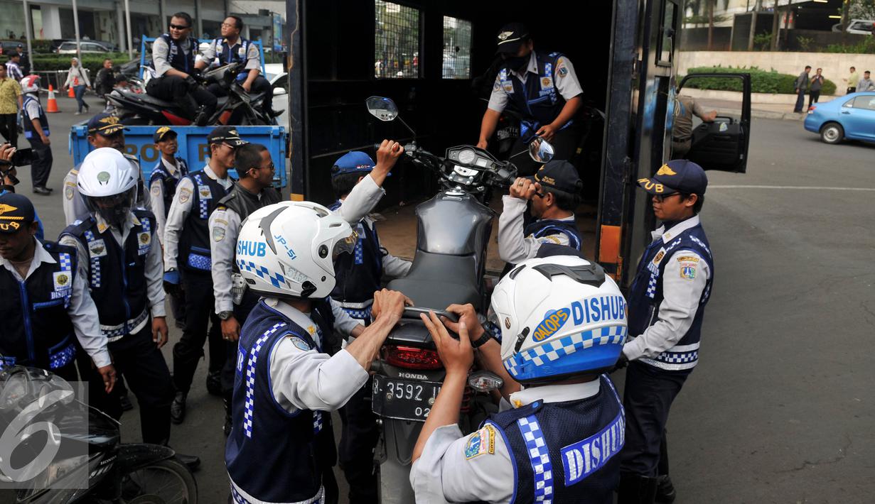Petugas Dishub, mengangkut sepeda motor saat razia gabungan di kawasan Tanah Abang, Jakarta, Jumat (12/6/2015). Razia gabungan Dishub, Garnisun dan Satlantas bertujuan untuk mengantisipasi arus lalu lintas yang kerap macet. (Liputan6.com/Johan Tallo)