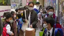 Siswa sekolah dasar mengantre untuk masuk bus sekolah di Hong Kong, Selasa (11/1/2022). Sekolah akan tutup mulai hari Jumat dan sampai setidaknya liburan Tahun Baru Imlek pada minggu pertama bulan Februari. (AP Photo/Kin Cheung)