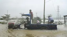 Warga menggunakan traktor untuk melintasi jalan yang tergenang banjir di kota Hpa Yar Gyi di wilayah Bago, Myanmar, pada tanggal 9 Oktober 2023. (SAI AUNG MAIN/AFP)