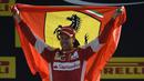 Sebastian Vettel dengan bendera Ferrari di podium pemenang Sirkuit Monza, Italia. Minggu (6/9/2015). (AFP Photo/Olivier Morin)